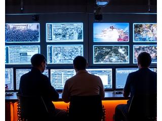 Close-up of a festival control center with people actively working on computers and communicating.